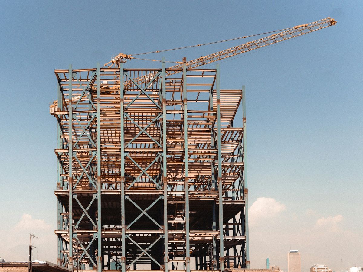 Steel frame of a building under construction, with a tower crane